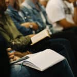 people sat in rows with notebooks and pens out