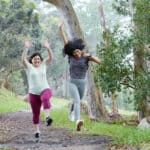 two women jumping in the air as they exercise in the woods