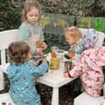 Four little girls sitting around a table in the woods