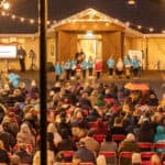 Mountbatten's Light up a life event with children ringing bells in front of a seat audience outside the hospice building