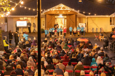 Mountbatten's Light up a life event with children ringing bells in front of a seat audience outside the hospice building