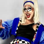 Quivers in drag makeup and bright blue outfit