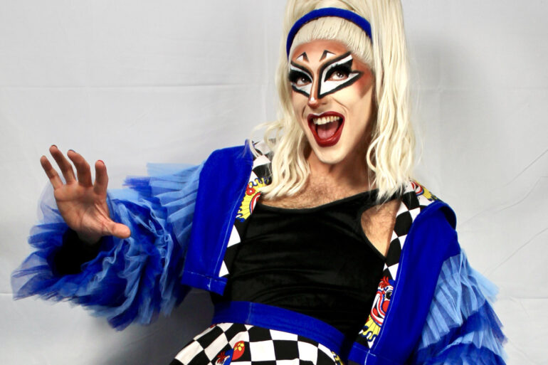 Quivers in drag makeup and bright blue outfit