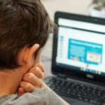 Young boy sitting at the dinner table working on his laptop