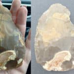 a Palaeolithic or pre-Palaeolithic hand axe in someone's palm and then beside a 50p piece