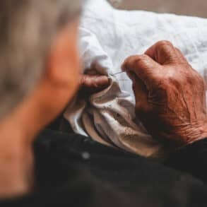 older person embroidering onto a white shirt by elio santos