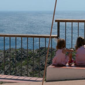 three young girls in the same dress - maybe triplets - looking out to sea