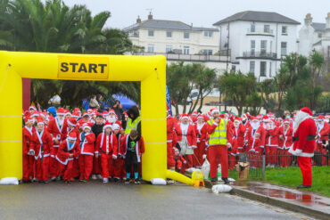 Children and adults dressed as santas, waiting at the start line of the Santa Dash race