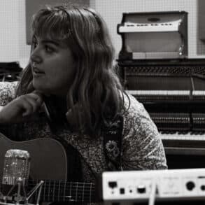 Black and white photo of young musician in the studio with guitar