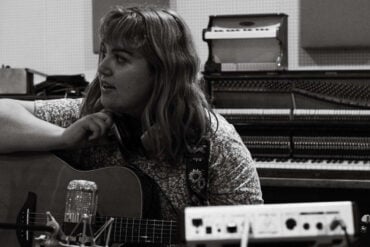 Black and white photo of young musician in the studio with guitar