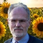 a field of sunflowers with photo of colin palmer in the foreground