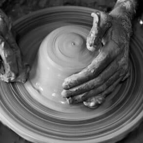 black and white photo of person throwing clay on a potters wheel