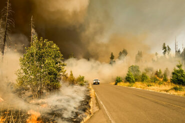 car driving through lots of smoke from wildfire
