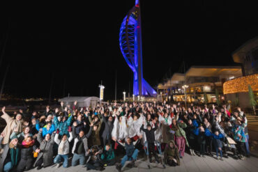 People posing for phot in front of Portsmouth's spinnaker tower