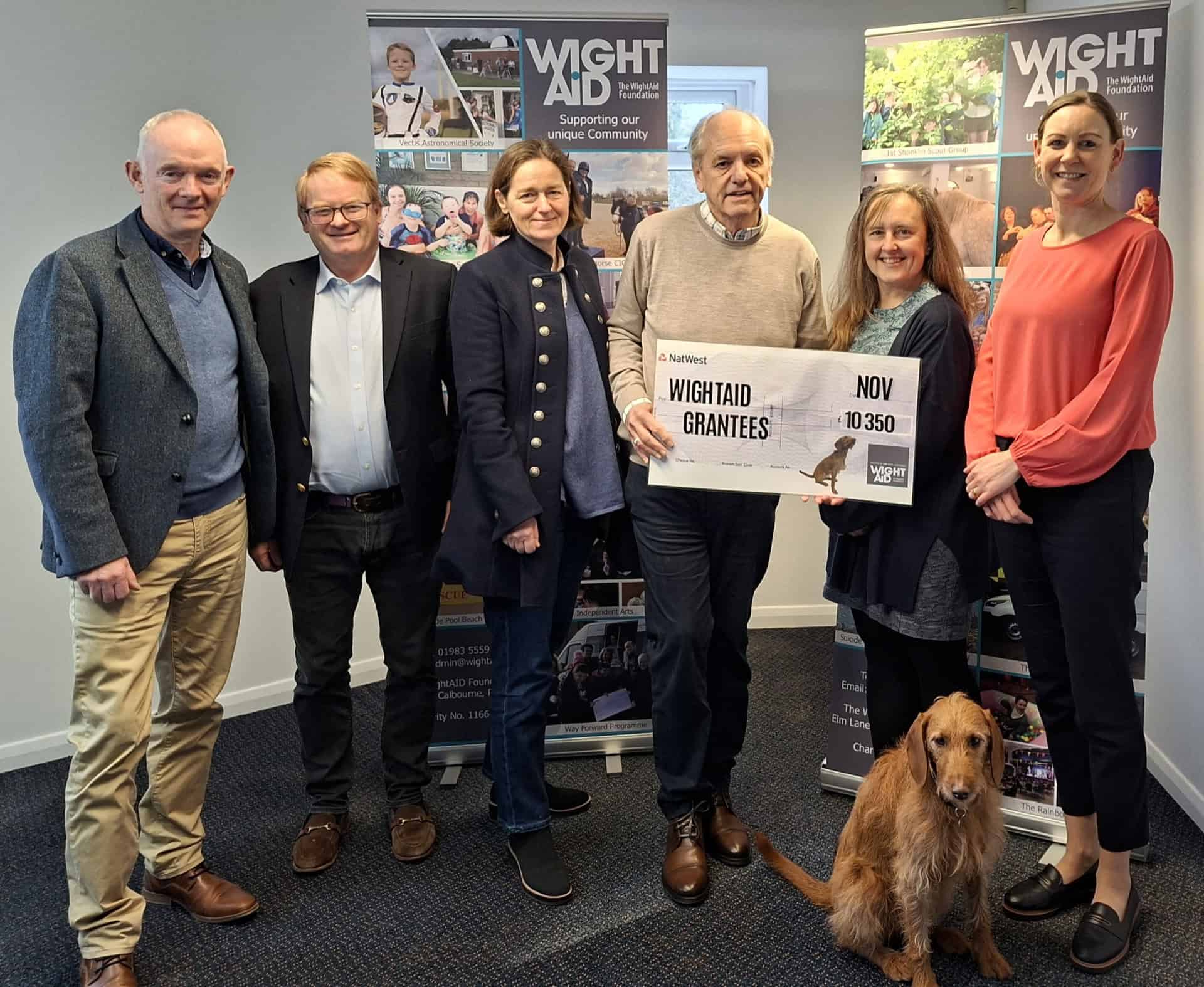 WightAID founder Geoff Underwood (left) and trustee David Jackson (third from right) with representatives of the Seaview Sailing Trust and Brighstone Primary School, plus Mavis the WightAID dog