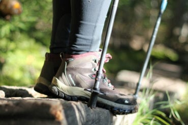 Person with walking boots on and holding hiking sticks