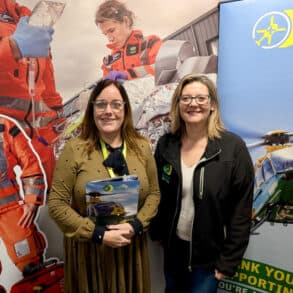 Two women standing in from of an Air Ambulance banner