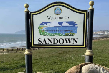 Welcome to Sandown sign with bay in the background