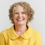 becky mcgregor portrait against a plain white background, showing Becky wearing a yellow jacket and smiling at the camera