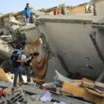 bombed homes in Gaza with young men climbing over the rubble searching for victims