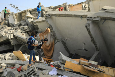 bombed homes in Gaza with young men climbing over the rubble searching for victims