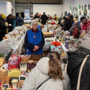 People huddling around the stalls at shanklin rotary sale - being held in an aircraft hanger