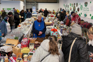 People huddling around the stalls at shanklin rotary sale - being held in an aircraft hanger