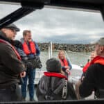 Professor Alice Roberts sitting on a boat in Ventnor harbour with a film crew around her