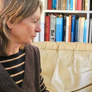 Maggie sitting in a chair by bookshelf at Art House Life