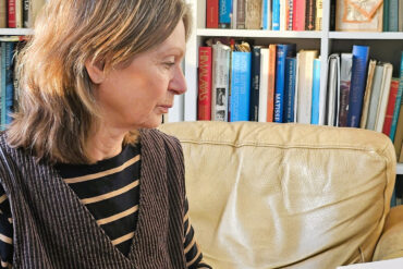 Maggie sitting in a chair by bookshelf at Art House Life