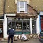 People standing around in shock after the bricks and masonry fell from above shop front