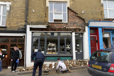 People standing around in shock after the bricks and masonry fell from above shop front