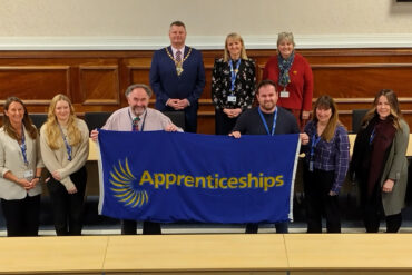 Councillors and staff holding up the national apprenticeship week flag