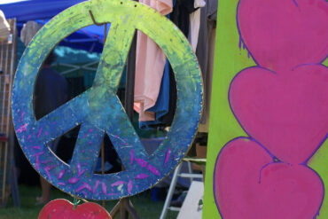 Large CND peace symbol and love hearts painted on plywood at Three Rivers Festival