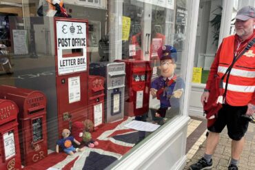 postman looking through the window at the postbox display