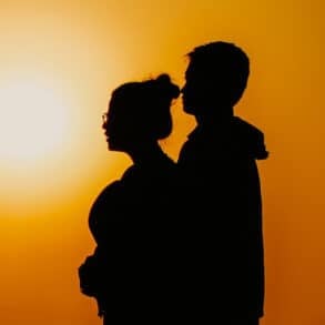 silhouette of man embracing woman as they look into the distance