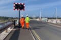 Two people in hi-viz jackets walking across Yarmouth Bridge