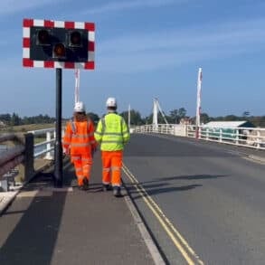Two people in hi-viz jackets walking across Yarmouth Bridge