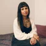 Young person sat on her bed in temporary accommodation