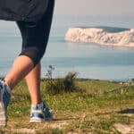 low down shot of a woman walking along a coastal path towards Tennyson Down