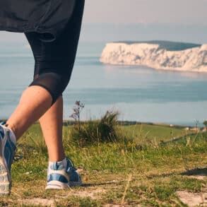 low down shot of a woman walking along a coastal path towards Tennyson Down