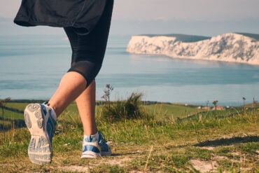 low down shot of a woman walking along a coastal path towards Tennyson Down
