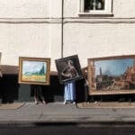 People standiNg on the street holding artworks
