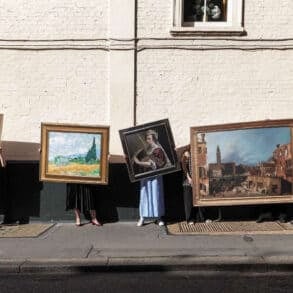 People standiNg on the street holding artworks