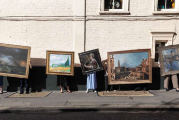 People standiNg on the street holding artworks