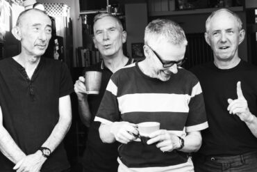 Black and white photo of band members of The Loft standing in a doorway