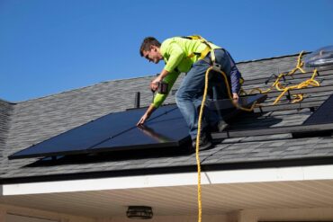 solar panel installer on the roof of a house