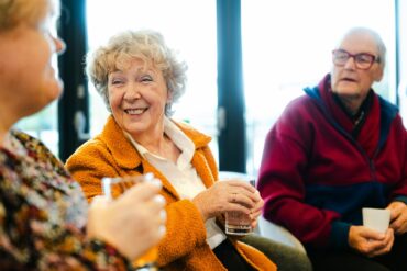 three older people drinking coffee and chatting