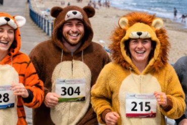 Four people in bear fancy dress running along the seafront