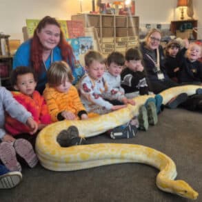 Photo of staff and pupils at Nursery school with giant snake